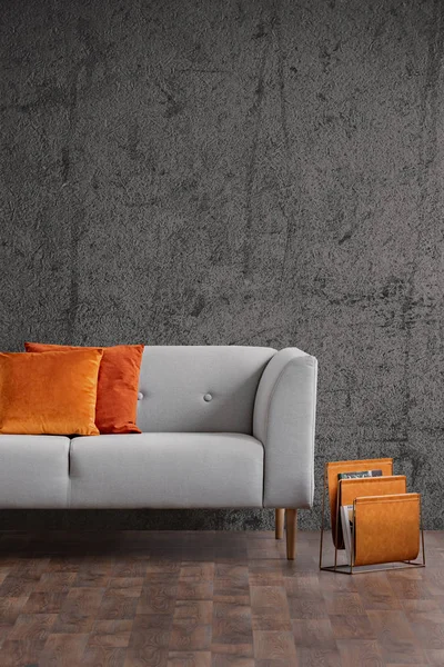 Orangefarbene Kissen auf grauer Couch im dunklen Loft-Interieur mit Betonwand und Holzboden. echtes Foto — Stockfoto