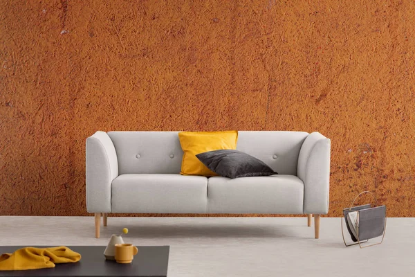 Interior de la sala de estar wabi sabi naranja quemada con sofá gris con almohadas amarillas y negras y estante de periódico — Foto de Stock