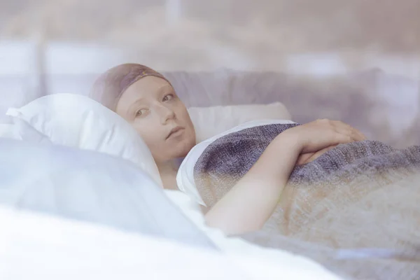 Femme réfléchie luttant contre la tumeur couchée dans un lit d'hospice — Photo