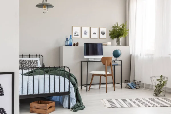 Wooden box under single metal bed with blue sheets and green blanket in trendy kid's room with workspace — Stock Photo, Image