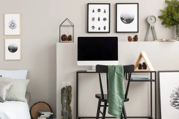Cônes sur étagère au-dessus du bureau avec tout en un ordinateur et triangle en bois, vraie photo avec des affiches sur le mur gris — Photo