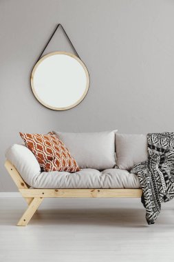 Yuvarlak ayna ışık gri kanepe yastık ile sahip aydınlık oturma odası iç duvarında ve gerçek fotoğraf battaniyeye asılı