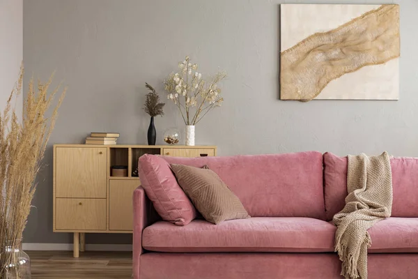 Gabinete de madera y pintura abstracta detrás del sofá rosa en el elegante interior de la sala de estar — Foto de Stock