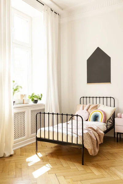 Planten op de vensterbank in kind slaapkamer interieur met zwarte poster boven bed met kussens. Echte foto — Stockfoto