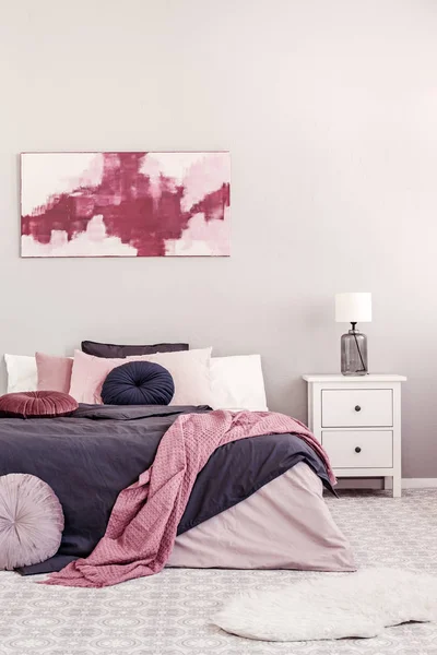 Абстрактная белая и бургундская живопись на стене стильного интерьера спальни с двуспальной кроватью — стоковое фото