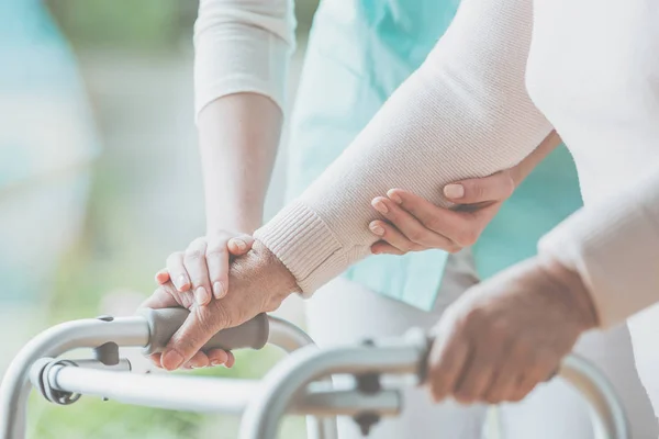 Closeup of grandmother's hands holding a walker and helpful granddaughter helping her — Stock Photo, Image