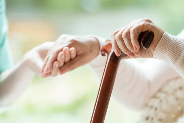 Close-up van senior oma houdt van walking cane in één hand en kleindochter de hand te houden in de andere — Stockfoto