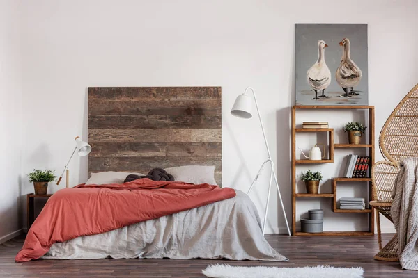 Comfortable king size bed with wooden rustic headboard and white industrial lamp next to it — Stock Photo, Image