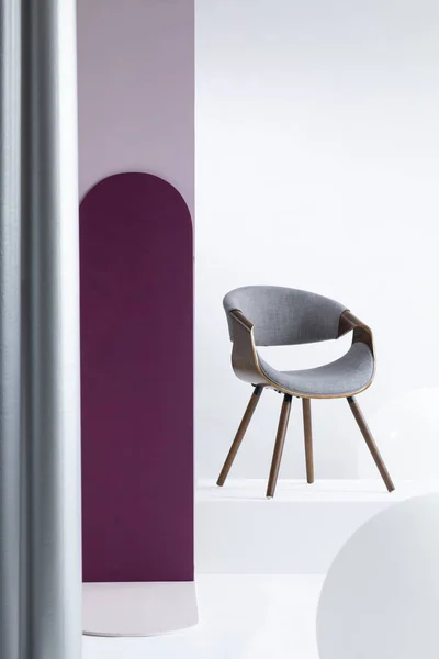 Pilier violet à côté d'une chaise grise dans un appartement lumineux intérieur avec des murs blancs. Une vraie photo — Photo