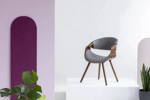 Véritable photo d'une chaise grise, polaire et cuir debout sur un podium dans un salon intérieur avec des plantes — Photo