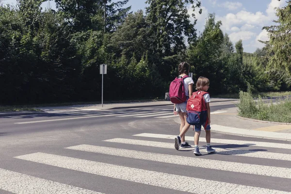 Crianças com mochilas caminhando pela travessia de pedestres para a escola — Fotografia de Stock