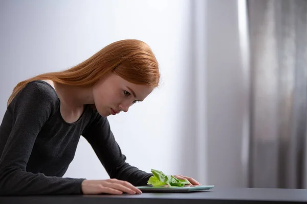 Junges Mädchen betrachtet den Salat auf einem Tisch — Stockfoto