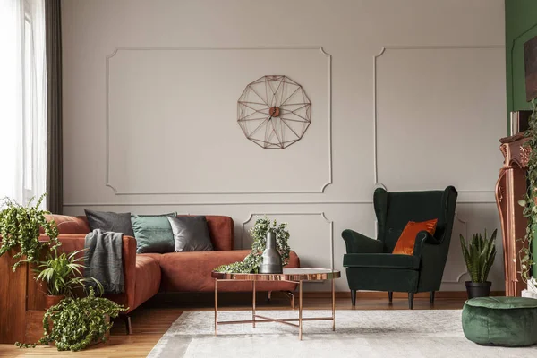 Velvet emerald green armchair with orange pillow next to corner sofa and coffee table — Stock Photo, Image