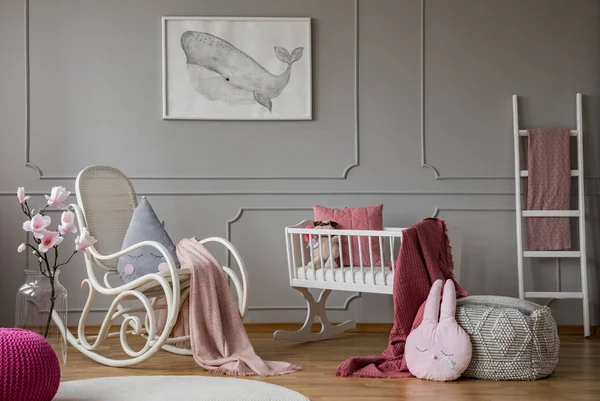 Flores y mecedora en el interior del dormitorio del bebé gris con póster y puf. Foto real —  Fotos de Stock