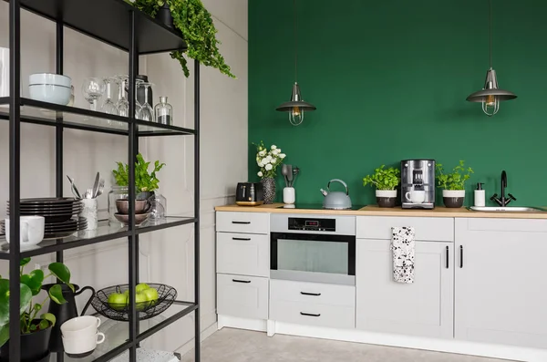 Dos lámparas industriales sobre muebles de cocina con hierbas, cafetera y rosas en jarrón, espacio de copia en la pared verde vacía — Foto de Stock