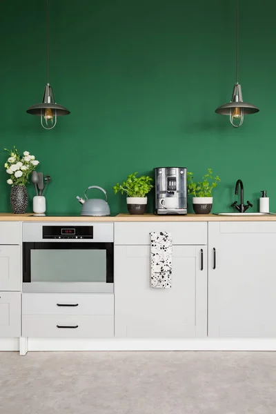 Deux lampes en métal au-dessus du comptoir de cuisine avec des herbes, une cafetière et des roses dans un vase, copiez l'espace sur un mur vert vide — Photo