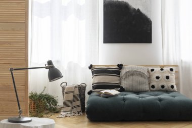 Şık oturma odası iç yastıklar ile İskandinav futon üzerinde siyah ve beyaz resim, boş duvara mockup ile gerçek fotoğraf
