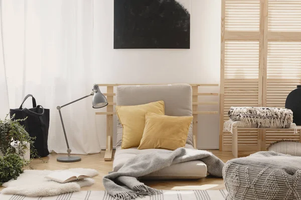 Almohadas amarillas y manta gris cálida sobre futón gris en el interior brillante dormitorio natural — Foto de Stock