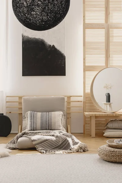 Pintura abstracta en blanco y negro en la pared en el interior del dormitorio luminoso con cama de futón y espejo en la mesita de noche —  Fotos de Stock