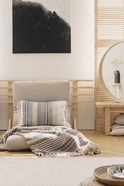 Pionowy widok czarno-białego abstrakcyjnego malarstwa nad białym ciepłym kocem i wzorzystą poduszką na beżu futon w eleganckiej naturalnej sypialni wnętrz, prawdziwe zdjęcie z makieta na pustej ścianie — Zdjęcie stockowe