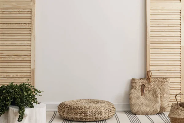 Parete bianca vuota tra schermo in legno in interni luminosi con pouf di vimini e sacchetti di paglia — Foto Stock