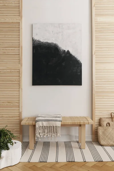 Pintura en blanco y negro sobre banco de madera con manta a rayas en la sala de espera natural, foto real con maqueta en la pared vacía —  Fotos de Stock