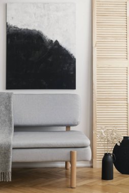 Gri şık kanepe ile doğal oturma odası iç beyaz duvar üzerinde soyut siyah ve beyaz boyama