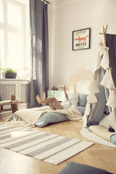 Jongen liggend op een bed en plezier in een Boho kamer interieur — Stockfoto