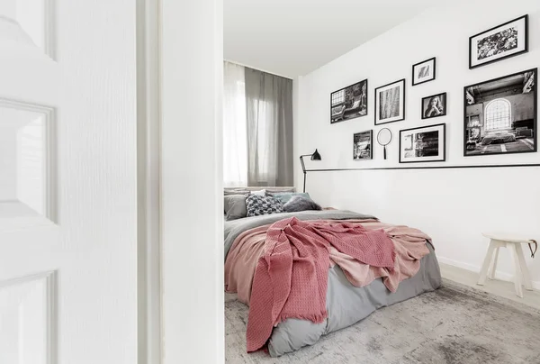 Galleria di manifesti su parete bianca in camera da letto moderna interni con lenzuola rosa sul letto. Foto reale — Foto Stock
