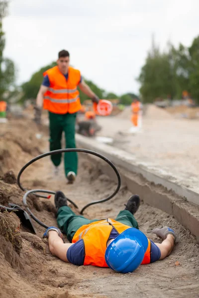 Incidente durante la costruzione di strade, lavoratore infortunato sdraiato a terra — Foto Stock