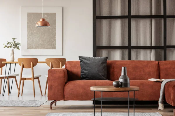 Open plan living and dining room interior with long table with chair and brown velvet settee