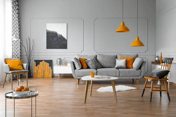 Просторная гостиная с журнальным столиком, стильными стульями и удобным диваном серого цвета — стоковое фото