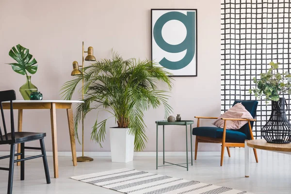 Silla en la mesa con hoja en el interior del apartamento con plantas, sillón de madera y póster. Foto real — Foto de Stock