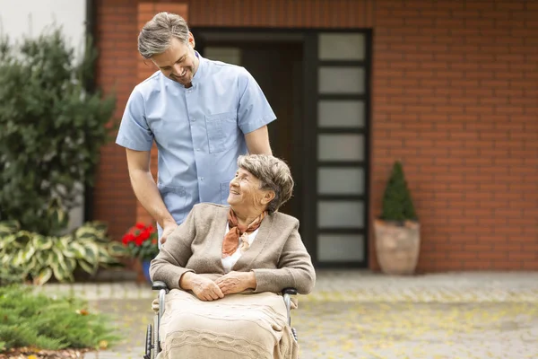 Медсестра помогает инвалидам счастливая пожилая женщина в инвалидном кресле — стоковое фото