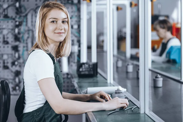 Closeup of concentrated young female worker in denim overall working at factory — Stock Photo, Image