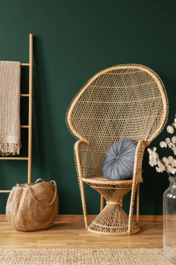 Rattan sandalye çanta ve çiçekler ve halı ile yeşil oturma odası iç merdiven yanında. Gerçek fotoğraf