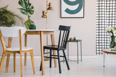 Pastel pembe duvara poster ile moda yemek odası iç cam vazo yeşil yaprak ile yuvarlak masada ahşap sandalye