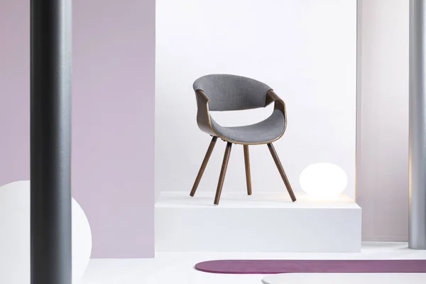 Véritable photo d'un intérieur simple, blanc et violet avec une chaise grise sur un podium — Photo