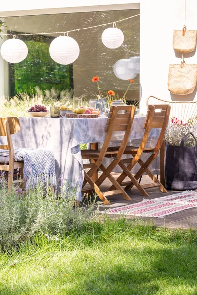 Lámparas de papel en una terraza con una mesa y sillas junto a un césped. Foto real — Foto de Stock