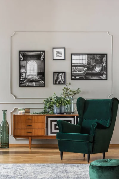 Poltrona verde esmeralda na elegante sala de estar com fotos em preto e branco na parede cinza e armário retro — Fotografia de Stock