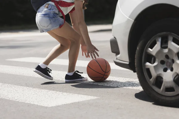 Miúdo descuidado segurando uma bola na passadeira na frente de um carro — Fotografia de Stock