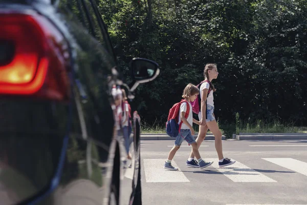 孩子们在一辆汽车旁穿过人行横道来到学校 — 图库照片