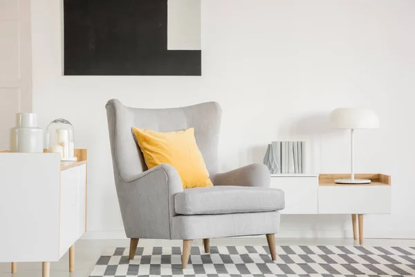 Travesseiro amarelo na poltrona cinza na sala de estar elegante interior com pintura em preto e branco — Fotografia de Stock