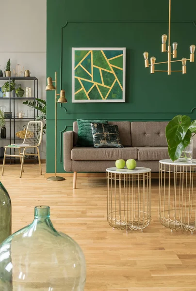 Elegant green and gold living room with comfortable brown sofa, coffee tables and golden chandelier — Stock Photo, Image