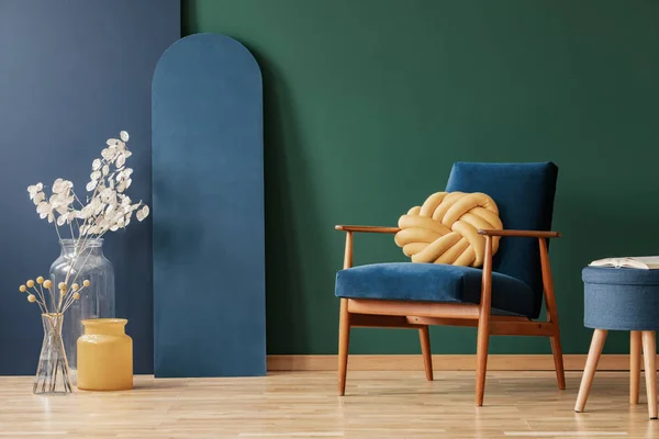 Almohada amarilla sobre sillón de madera en interior plano azul y verde con flores y taburete. Foto real —  Fotos de Stock