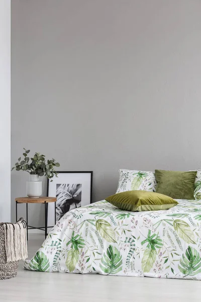침구와 올리브 녹색 베개에 잎 패턴이 있는 아늑한 침실의 빈 회색 벽에 복사 공간 — 스톡 사진