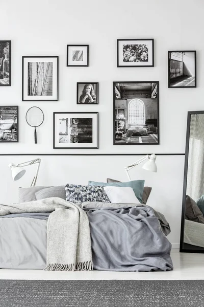 Tapete cinza na frente da cama e espelho no interior do quarto branco e preto com galeria. Foto real — Fotografia de Stock