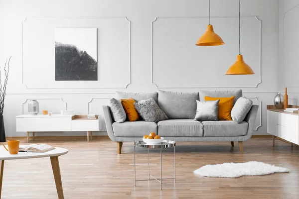 Real foto av en modern vardags rum interiör med en soffa, orange lampor och målning — Stockfoto