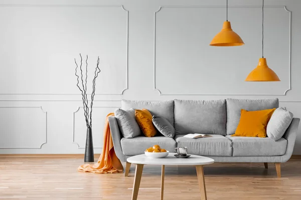 Véritable photo de salon simple intérieur avec lampes orange, oreillers et canapé gris — Photo