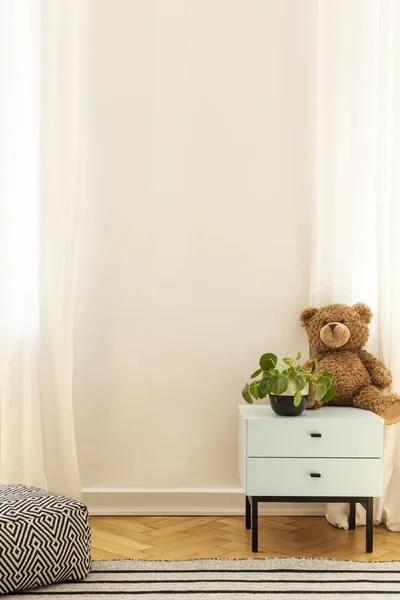 Plant en pluche speelgoed op blauwe kast in de kamer kid's interieur met poef en kopieerruimte op de muur. Echte foto — Stockfoto